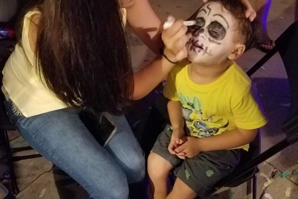 A kid getting face painting from Joy of Life employee - Joy of Life Surrogacy