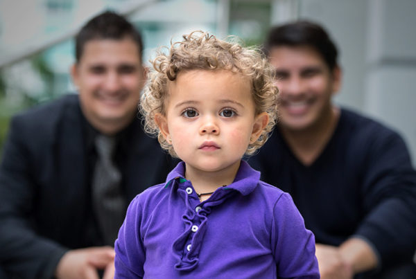 A little baby standing in front of his same-sex parents - Joy of Life Surrogacy