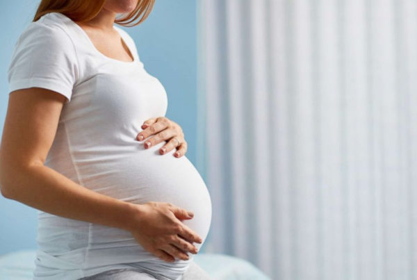 一位怀孕的妈妈穿着白色T恤坐在床上 - Joy of Life 代孕