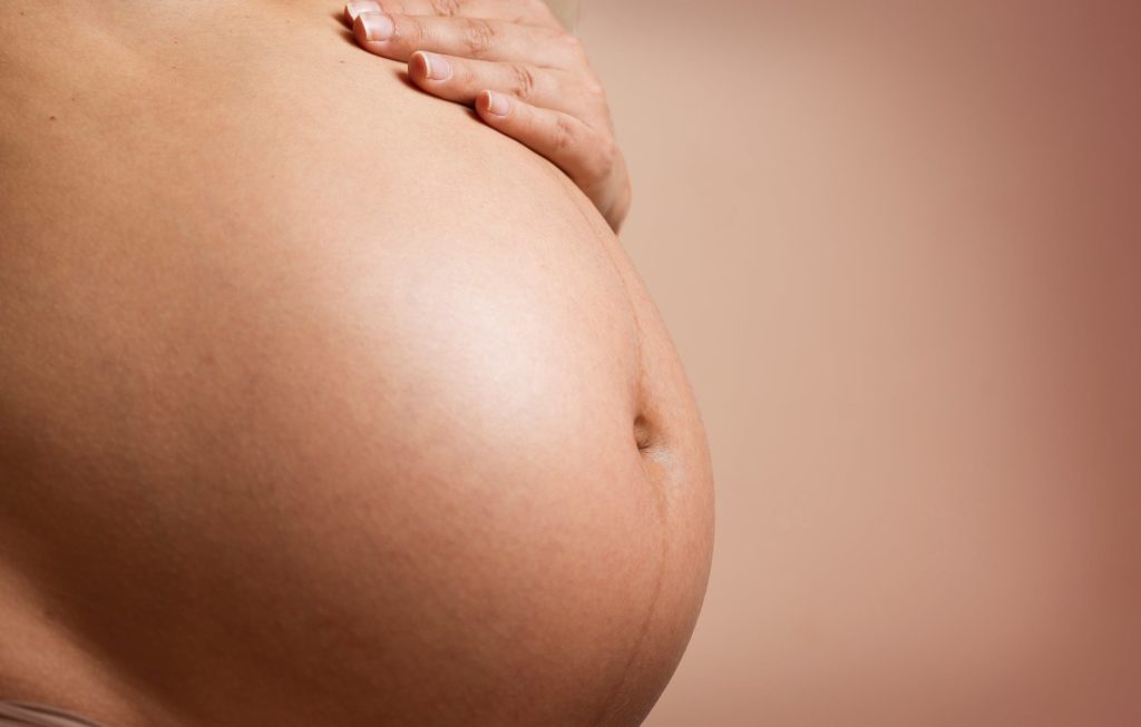 Una madre embarazada parada frente a la cámara. Joy of Life® Subrogación