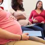 A gathering of expectant surrogate mothers seated comfortably and holding informational folders.