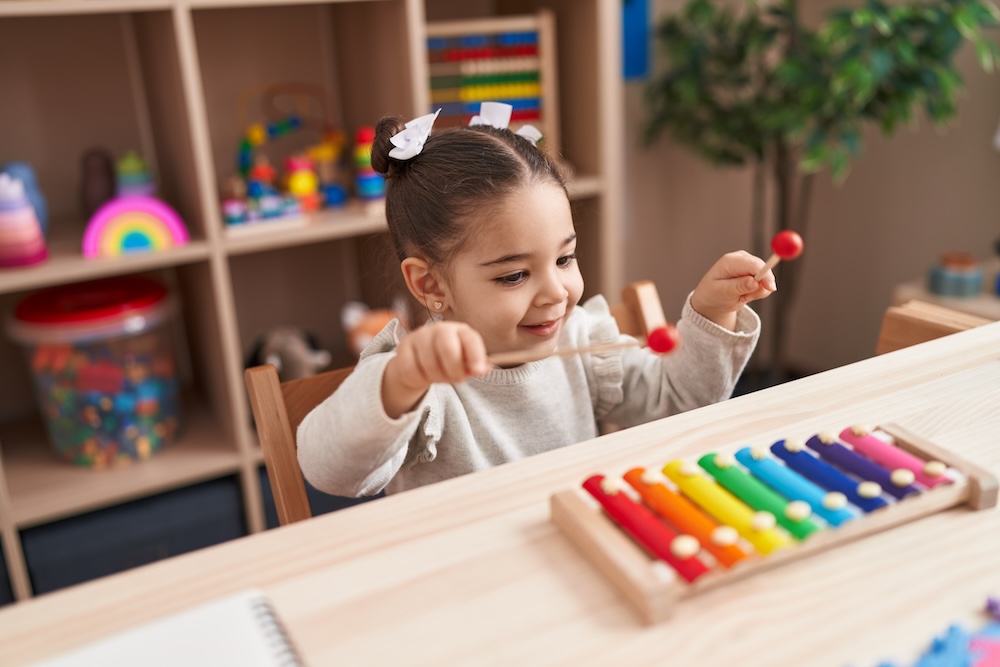 Little girl playing a rainbow xylophone