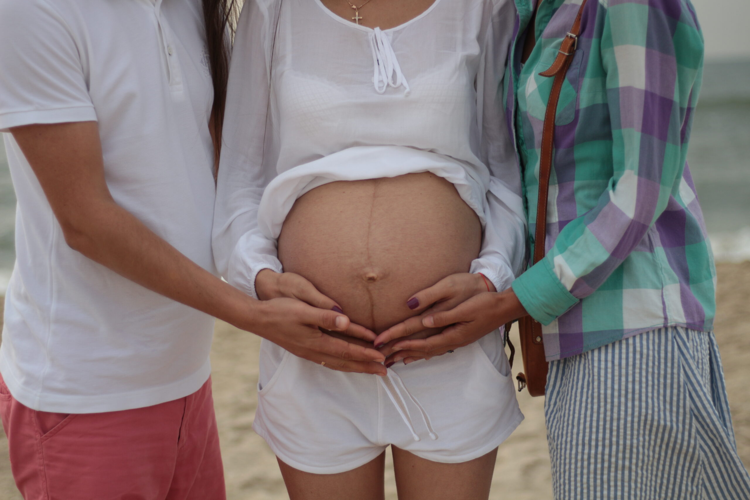 三个人抱着一个女人怀孕的肚子。