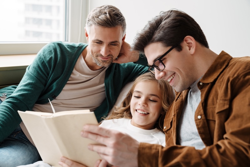 快乐的同性恋父母和女儿一起在家读书