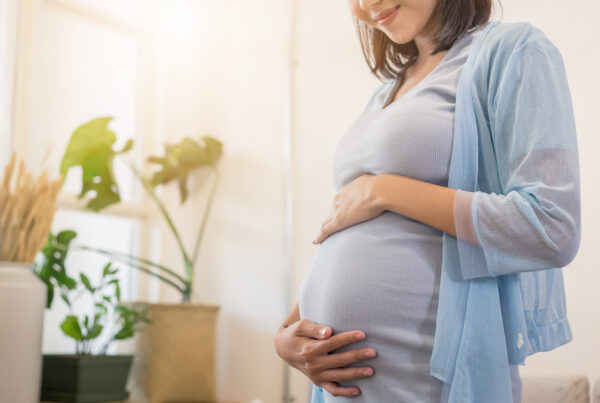 Pregnant woman smiling with hands placed on stomach