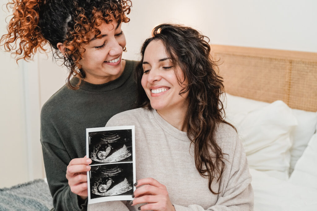 两名妇女微笑着看着胎儿的超声波图像。