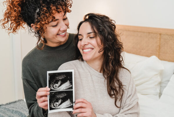 两名妇女微笑着看着胎儿的超声波图像。
