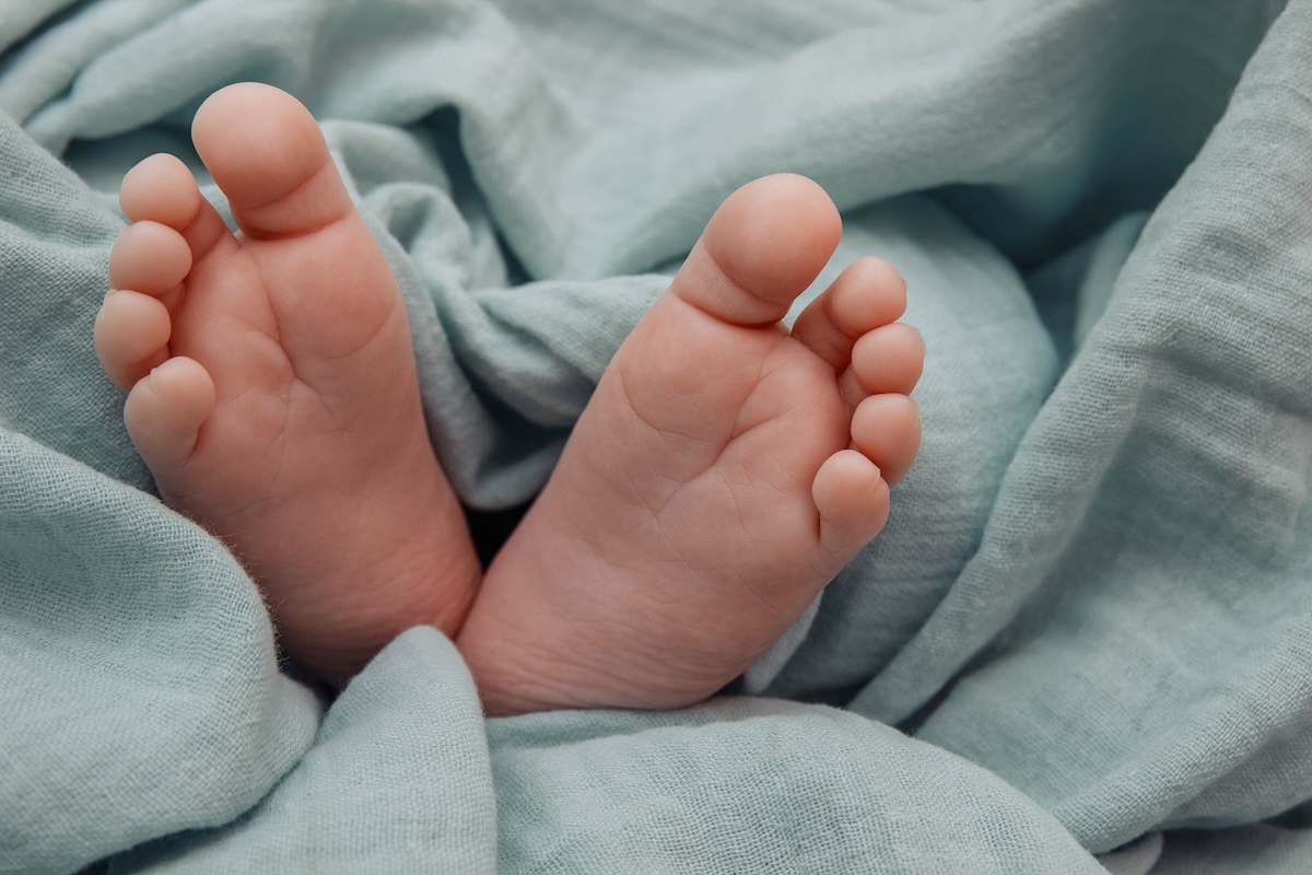Close-up of a baby's feet wrapped in a soft, light blue blanket.