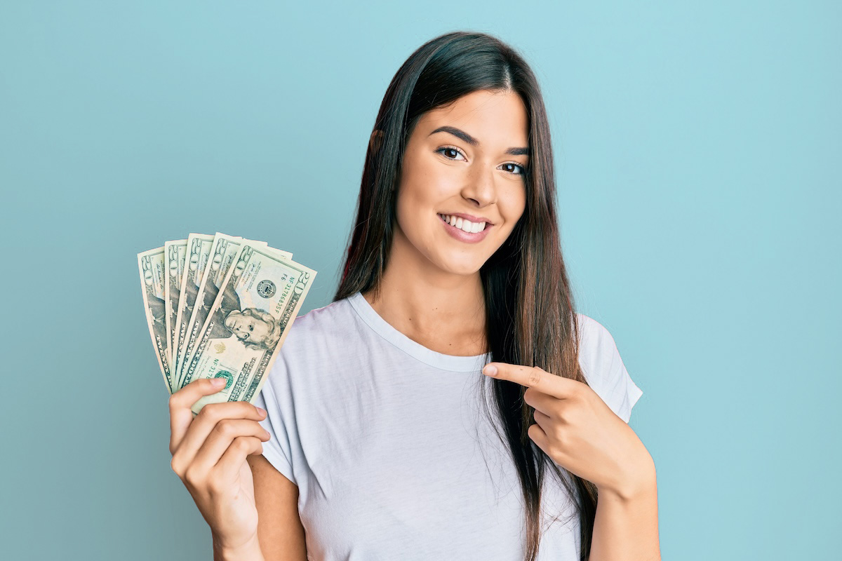 Woman holding cash and smiling