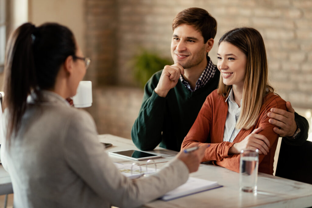 Smiling intended parents meet with a professional across a desk to discuss surrogacy laws and their options for growing a family.