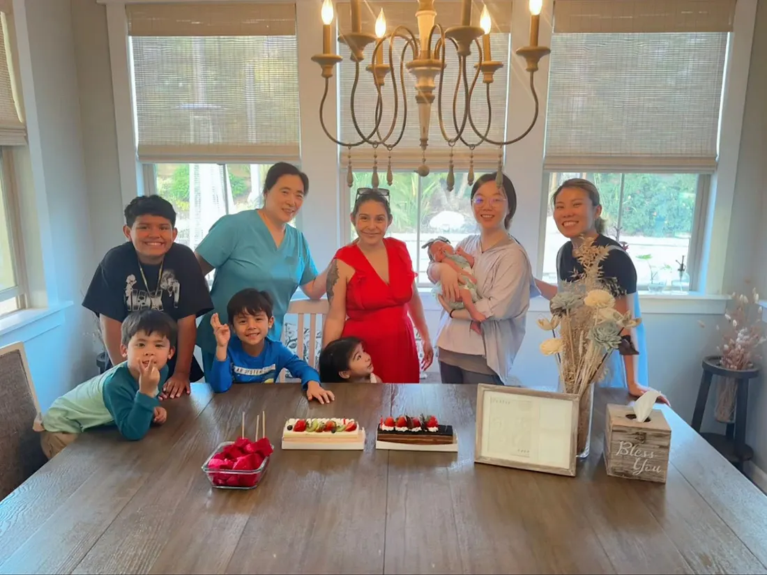 Joy of Life® Featured for Building Lifelong Bonds 1 A joyful group gathered around a dining table celebrating together, including several children, two women, and a newborn baby.