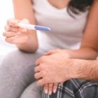 Honoring World Infertility Awareness Month This June 1 Person holding a pregnancy test while sitting beside a partner, reflecting a hopeful fertility or family-building moment.