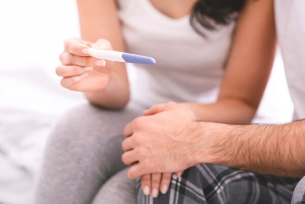 Honoring World Infertility Awareness Month This June Person holding a pregnancy test while sitting beside a partner, reflecting a hopeful fertility or family-building moment.